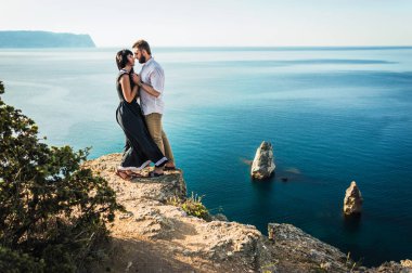 Deniz kenarında bir uçurumun üzerinde çift duruyor