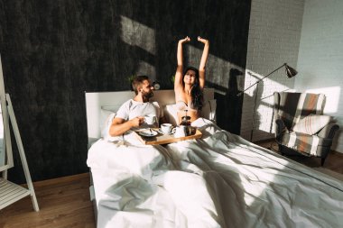 Loving couple having breakfast in bed. Guy and girl in bed. Breakfast in bed. Tea in bed. The relationship between a man and a woman. Loving couple. Morning lovers. Family relationships. Good morning