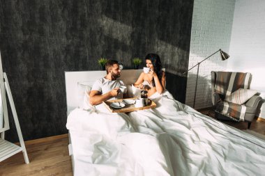 Loving couple having breakfast in bed. Guy and girl in bed. Breakfast in bed. Tea in bed. The relationship between a man and a woman. Loving couple. Morning lovers. Family relationships. Good morning