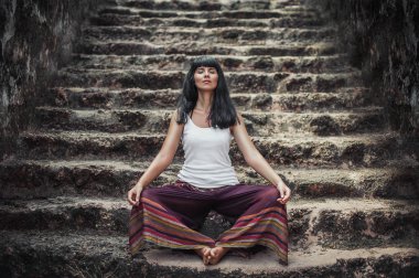 Lotus pozisyonu kız. Çekici kız yoga yapıyor. Sağlıklı bir yaşam tarzı. Bir kişi tapınakta derin derin düşünür. Vücut konsantrasyonu. Tatil Asya. Eski tapınağın merdiven. Budist Tapınağı