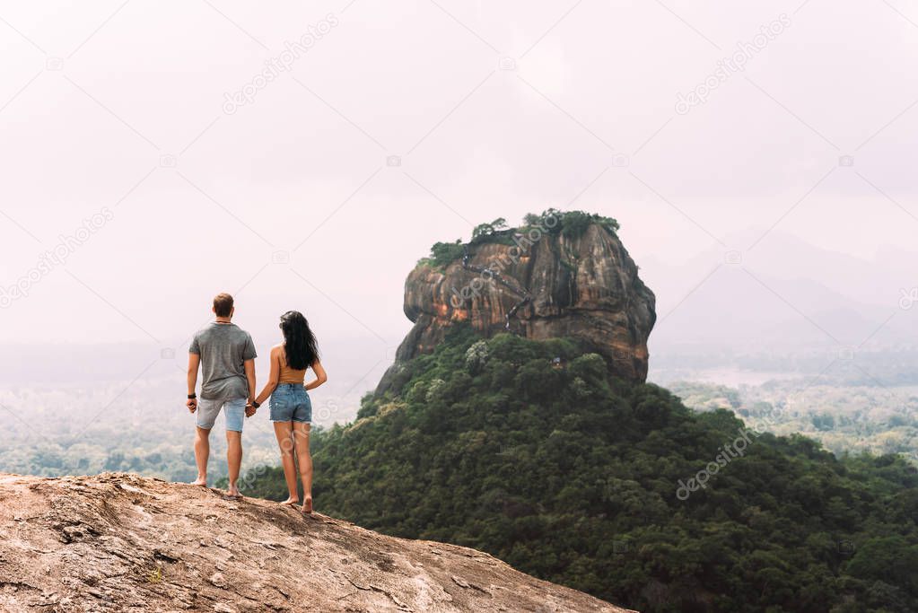 Man and woman stand on the rock and admire the panoramic view. A couple in love on a rock admires the beautiful views. A couple in love travels. Couple in Sri Lanka. Honeymoon in Asia. Wedding travel