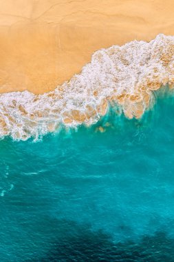 Turkuaz denizi ve dikey manzaralı güzel kumlu bir sahil. Tropikal turkuaz okyanus plajı Nusa Penida Bali Endonezya 'nın insansız hava aracı görüntüsü. Güzel dalgaları olan ıssız kumlu bir sahil. Endonezya plajları.