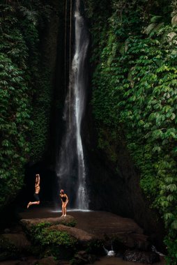 Bali 'de şelalede eğlenen mutlu çift. Endonezya 'da şelalede eğlenen bir çift. Bir erkek ve bir kadın dünyayı dolaşır. Tatildeki mutlu çift. Bali adasında tatil..