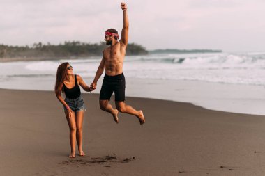 Kumsaldaki mutlu çift. Birbirine aşık bir çift kumsalda eğleniyor. Gün batımında kadın ve erkek. Sahildeki adam ve kız. Çift Bali Endonezya adasında tatil yapıyor. Asya 'da tatiller