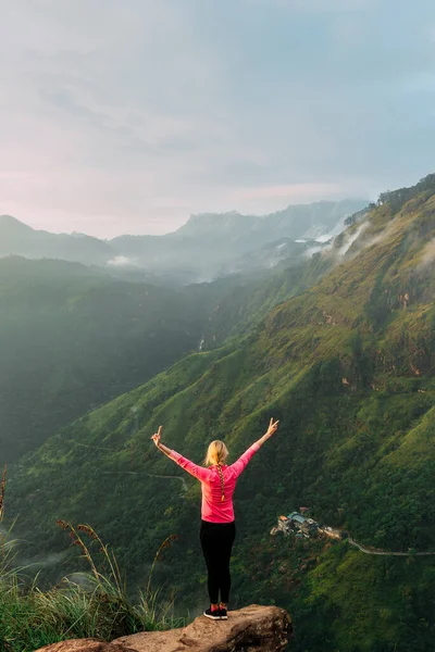 Woman meets sunrise in the mountains. Girl traveling to Sri Lanka. Mountain sports. Athlete happy finish. Mountain tourism. Walking tour. The journey to the mountains. Crossfit in the mountains