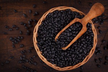 Kepçe ahşap arka plan üzerinde siyah fasulye