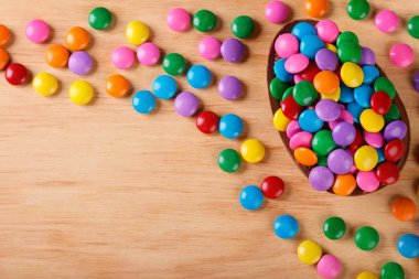 Tahta arka planda Paskalya için renkli şekerlerle dolu çikolatalı yumurta. Seçici odaklanma. Boşluğu kopyala