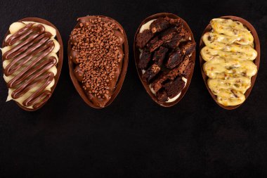 Siyah arka planda Paskalya için tugayla doldurulmuş çikolatalı yumurta. Seçici odaklanma. Boşluğu kopyala