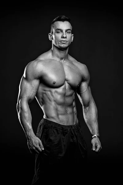 Foto en blanco y negro de Muscular y ajuste modelo fitness joven posando sobre fondo negro . — Foto de Stock