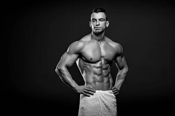 Schwarz-Weiß-Foto eines muskulösen und fitten jungen Fitnessmodels, das vor schwarzem Hintergrund posiert. — Stockfoto