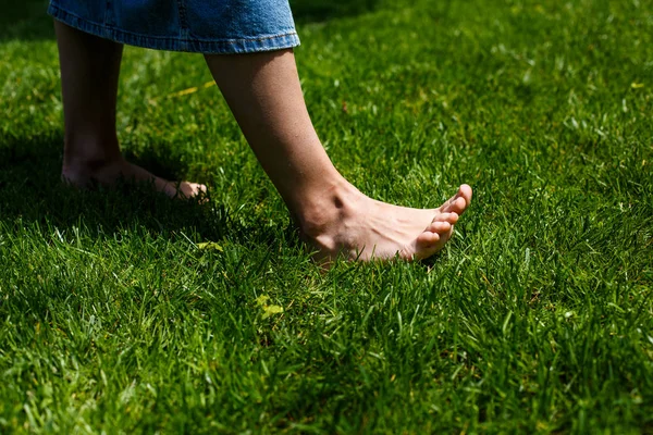 Pernas femininas na grama verde — Fotografia de Stock