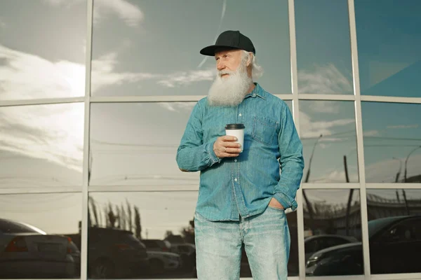 Старик с бородой и кофе в руках — стоковое фото