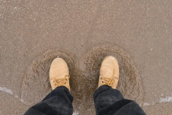 Глядя на пару коричневых кожаных туфель, стоящих на песчаном пляже океана. Летние каникулы . — стоковое фото