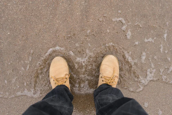 Глядя на пару коричневых кожаных туфель, стоящих на песчаном пляже океана. Летние каникулы . — стоковое фото