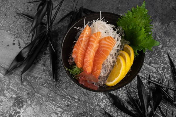 Sashimi with Tuna with slice of lemon fresh greens on bamboo leaf and in plate full of ice. — Stock Photo, Image