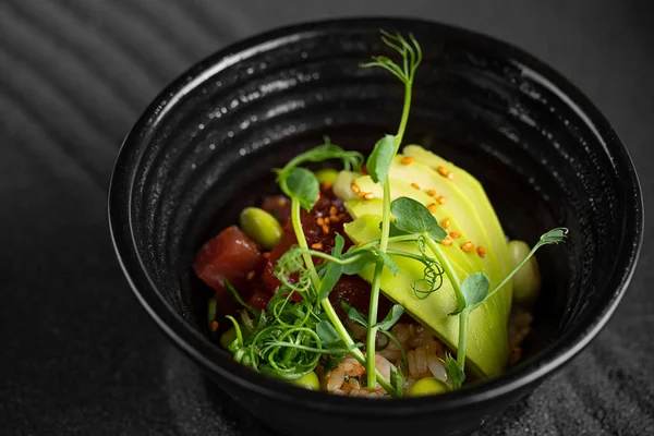Poke bowl Ensalada de pescado crudo Comida asiática de moda con frijoles de soja edamame, arroz, aguacate y lechuga en un tazón sobre fondo oscuro — Foto de Stock