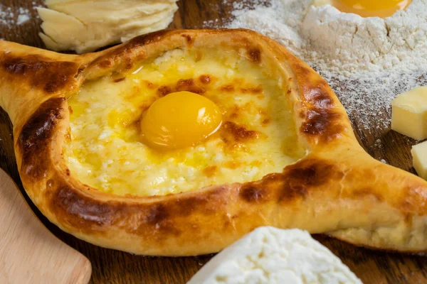 아담 한 치즈와 달걀 노른자와 버터를 얇게 썰어 넣은 아담 한 널빤지 위에 밀가루를 뿌려 놓은 나무 도마 위에 놓여져 있다. — 스톡 사진