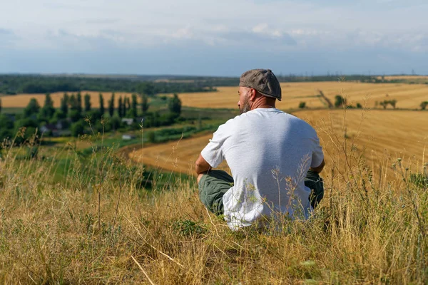 Giovane uomo in nero abbigliamento sportivo è seduto sul bordo della scogliera e guardando nebbioso valle soffietto — Foto Stock