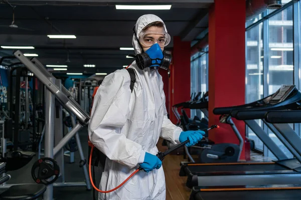 プロの消毒剤個人用保護具銅スーツ マスク 加圧スプレー消毒水でジムのスペースを掃除してCovid 19コロナウイルスを除去する — ストック写真