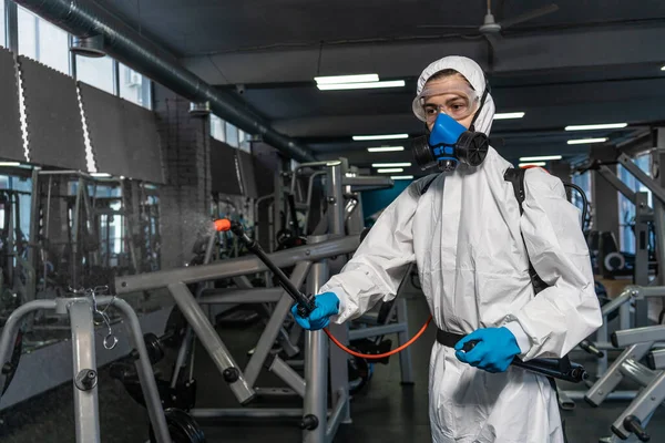 プロの消毒剤個人用保護具銅スーツ マスク 加圧スプレー消毒水でジムのスペースを掃除してCovid 19コロナウイルスを除去する — ストック写真