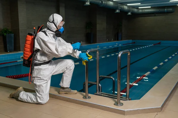 コロナウイルス流行中のプールでの清掃と消毒ジムの清掃と消毒感染予防と流行の制御 保護スーツとマスクとスプレーバッグ Covid — ストック写真