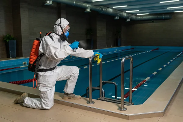 Cleaning and Disinfection in pool amid the coronavirus epidemic Gym cleaning and disinfection Infection prevention and control of epidemic. Protective suit and mask and spray bag COVID-19
