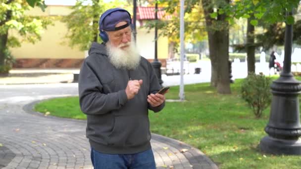 Starší Muž Poslouchá Hudbu Procházející Podzimním Parku — Stock video