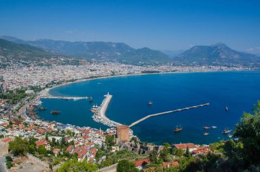 Türkiye 'nin Antalya ilçesindeki Alanya Kalesi' nin güzel deniz manzarası. Dağların arkasındaki antik şato. Yaz güneşli bir gün ve deniz kıyısında. Alanya, Antalya 'daki Kizil Kule (Kızıl Kule), Alanya Limanı' nın Türk manzarası gün batımından önce.
