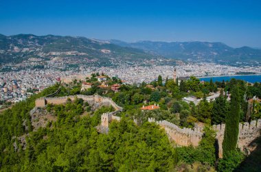 Türkiye 'nin Antalya ilçesindeki Alanya Kalesi' nin güzel deniz manzarası. Dağların arkasındaki antik şato. Yaz güneşli bir gün ve deniz kıyısında. Alanya, Antalya 'daki Kizil Kule (Kızıl Kule), Alanya Limanı' nın Türk manzarası gün batımından önce.