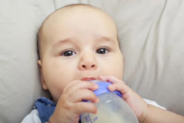 Lille gutt som drikker melk fra flasken – stockfoto
