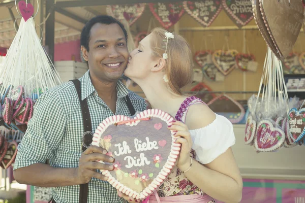 Interracial couple with traditional Oktoberfest gingerbread heart Lebkuchenherz — Stock Photo, Image