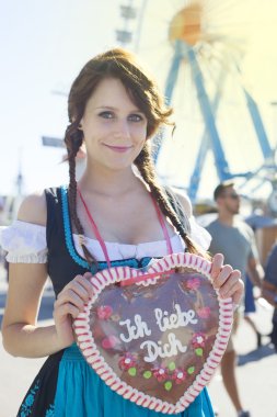 Bir Dirndl giyen ve bir geleneksel Oktoberfest'ın gingerbread kalp tutan Alman kız