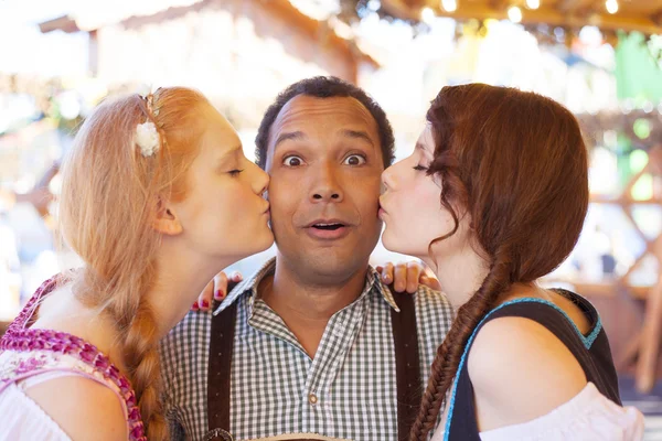 A fiatalember kezd megcsókolta az arcát két német lányok az Oktoberfest — Stock Fotó