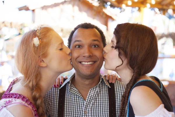 A fiatalember kezd megcsókolta az arcát két német lányok az Oktoberfest — Stock Fotó