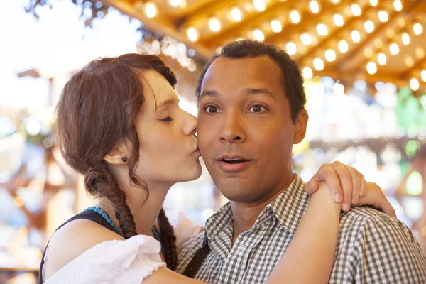 Young man getting kissed on the cheek by german girl at Oktoberfest — Stock Photo, Image