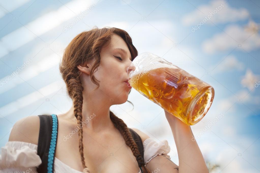 Young German woman drinking beer at Oktoberfest
