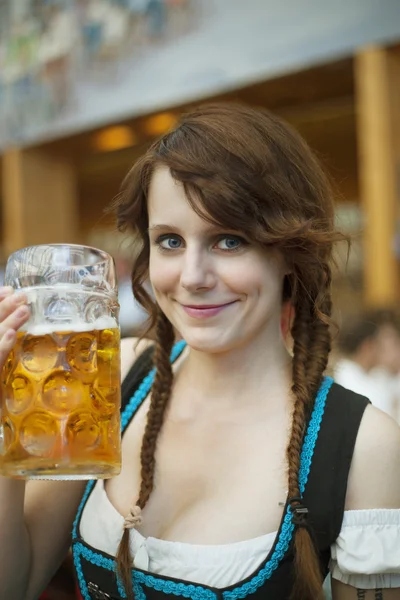 Retrato de una joven alegre vestida con dirndl tradicional y sosteniendo un stein de cerveza de 1 litro en el Oktoberfest —  Fotos de Stock