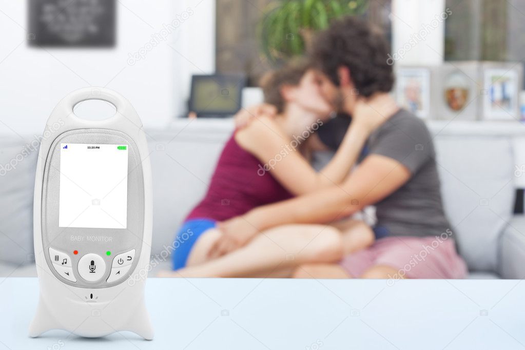 Baby monitor with copy space, with teenager babysitter and boyfriend enjoying free time on the background