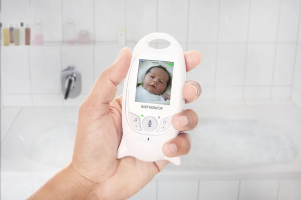 Nadřazený kontrolu novorozence prostřednictvím elektronické chůvy, krátce předtím, než si bere koupel — Stock fotografie