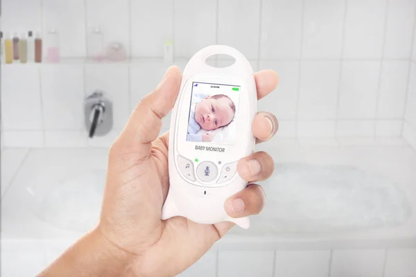 Parent checking newborn through baby monitor shortly before she takes a bath — Stock Photo, Image