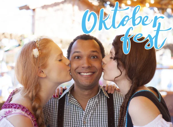 Jovem beijado na bochecha por duas garotas alemãs no Oktoberfest — Fotografia de Stock