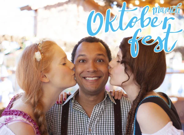 Jovem beijado na bochecha por duas garotas alemãs no Oktoberfest — Fotografia de Stock