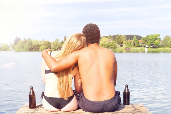 Giovane coppia che beve una birra vicino ad un lago — Foto Stock