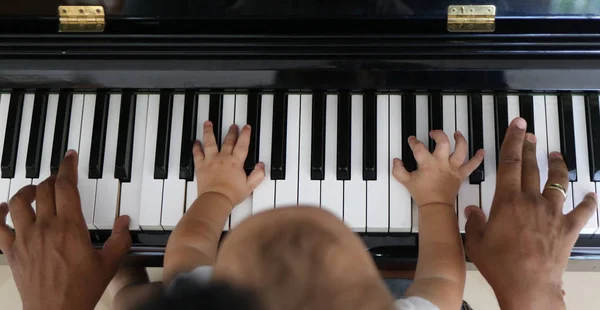 Тоддлер учится играть на пианино с отцом — стоковое фото