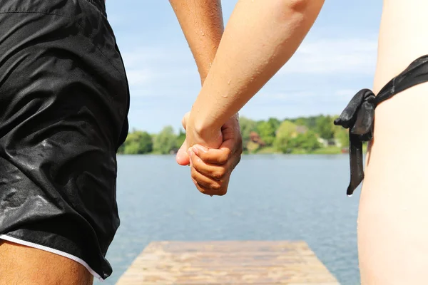 Pareja cogida de la mano a punto de saltar al agua — Foto de Stock