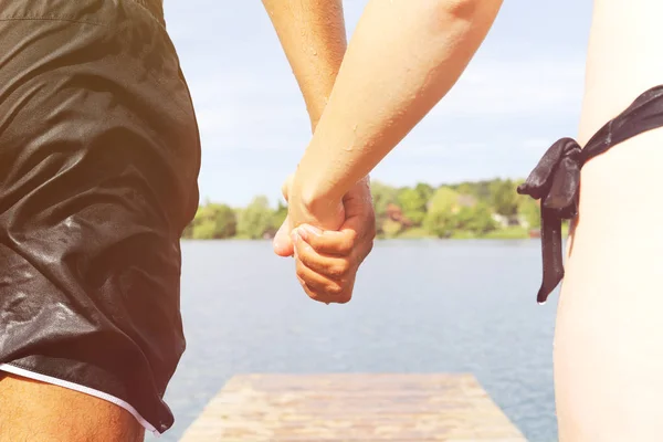 Coppia che si tiene per mano per saltare in acqua — Foto Stock