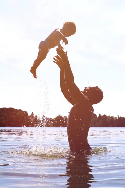 Famiglia felice trascorrere del tempo insieme su un lago - gettando bambino in alto — Foto Stock
