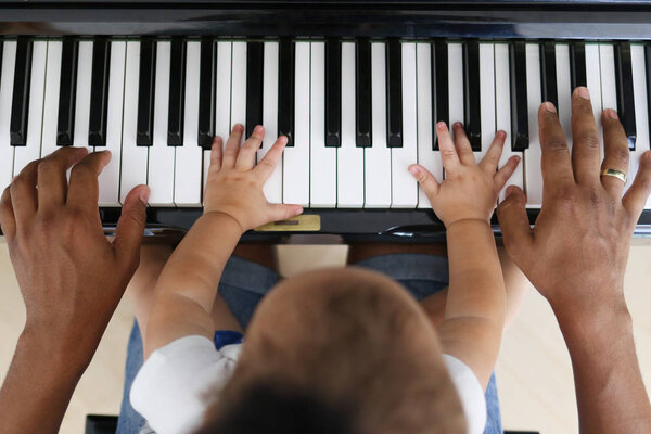 Toddler learning to play piano with father Royalty Free Stock Images