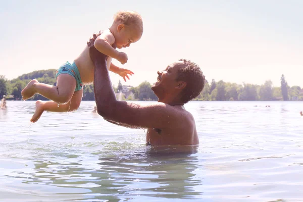 O familie fericită petrecând timp împreună pe un lac aruncând copilul în sus Fotografie de stoc