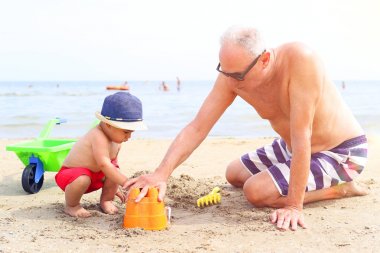 Küçük çocuk ve plajda oynayan dedesi